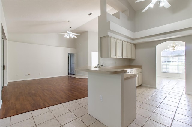 kitchen with kitchen peninsula, light hardwood / wood-style floors, cream cabinetry, a breakfast bar area, and ceiling fan with notable chandelier