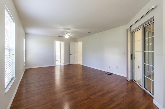 empty room featuring a wealth of natural light, ceiling fan, and dark hardwood / wood-style floors