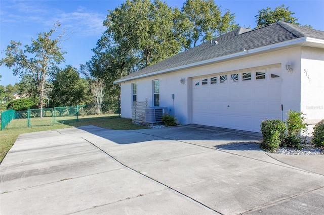 view of side of property with a lawn, cooling unit, and a garage