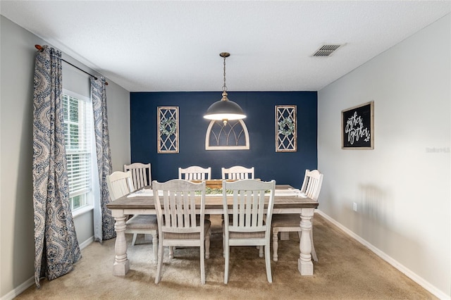 dining area featuring light colored carpet and a textured ceiling