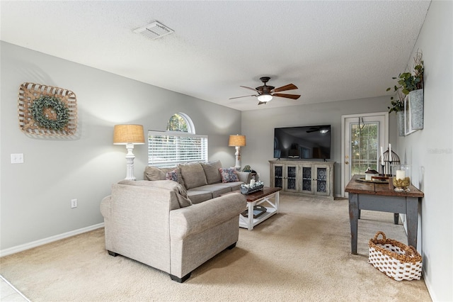 carpeted living room featuring ceiling fan and a textured ceiling