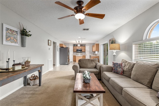 living room with ceiling fan, light colored carpet, and a textured ceiling