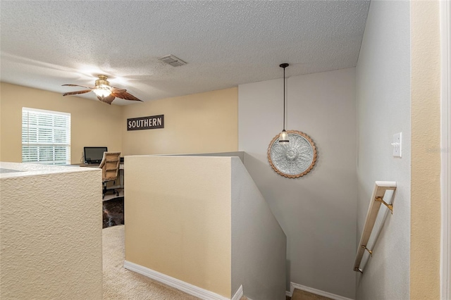 interior space with ceiling fan, carpet, built in desk, and a textured ceiling