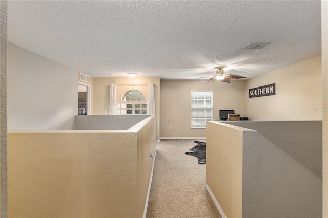 hallway featuring light carpet and a textured ceiling