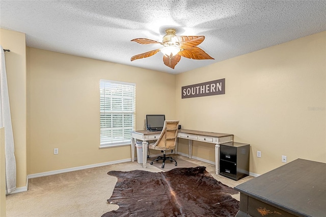 office area with a textured ceiling, light colored carpet, and ceiling fan