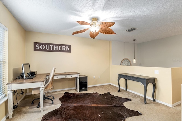 carpeted office space with a textured ceiling and ceiling fan