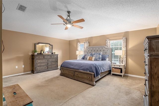 bedroom featuring ceiling fan, light colored carpet, and a textured ceiling