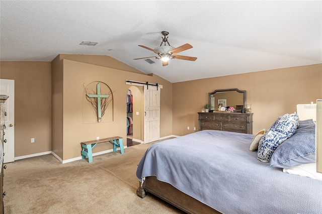 carpeted bedroom with a barn door, ceiling fan, and lofted ceiling