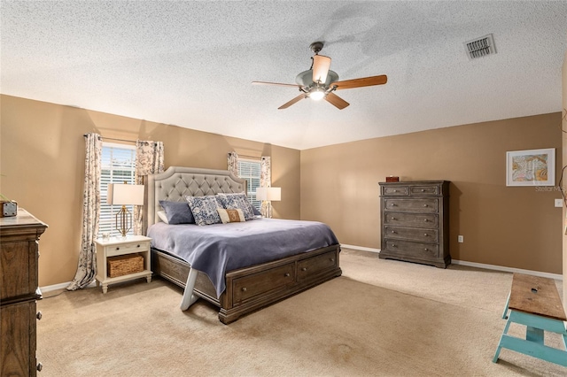 bedroom featuring a textured ceiling, light colored carpet, and ceiling fan