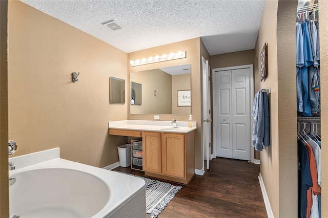 bathroom with hardwood / wood-style floors, vanity, a textured ceiling, and a bathing tub