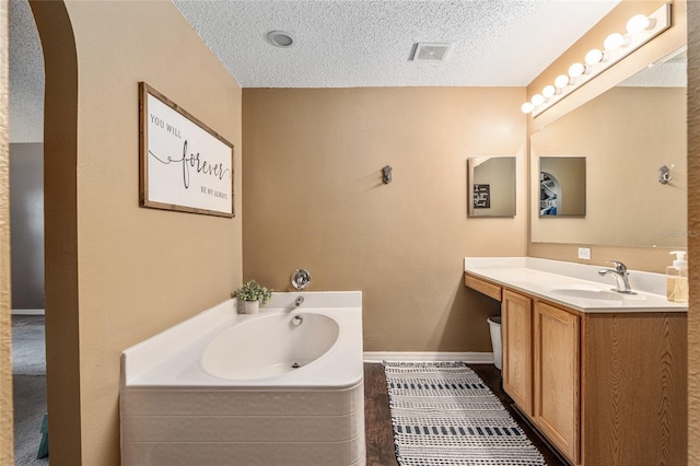 bathroom with a bathtub, vanity, and a textured ceiling