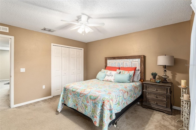 carpeted bedroom with a closet, ceiling fan, and a textured ceiling