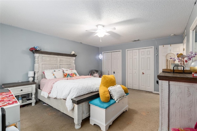 bedroom featuring two closets, a textured ceiling, ceiling fan, and carpet