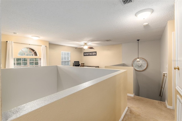 corridor featuring a textured ceiling and light colored carpet