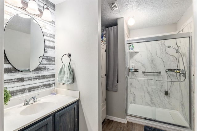 bathroom with vanity, a textured ceiling, hardwood / wood-style flooring, and a shower with shower door