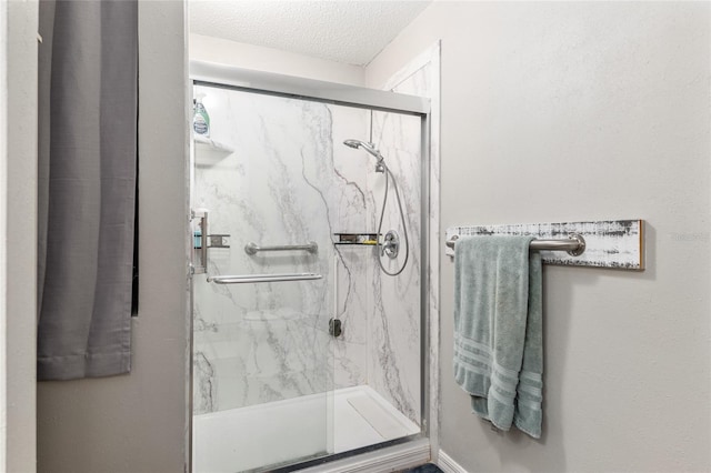 bathroom featuring a shower with shower door and a textured ceiling