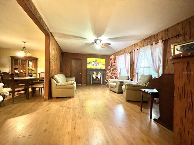 living room with wooden walls, hardwood / wood-style floors, and ceiling fan