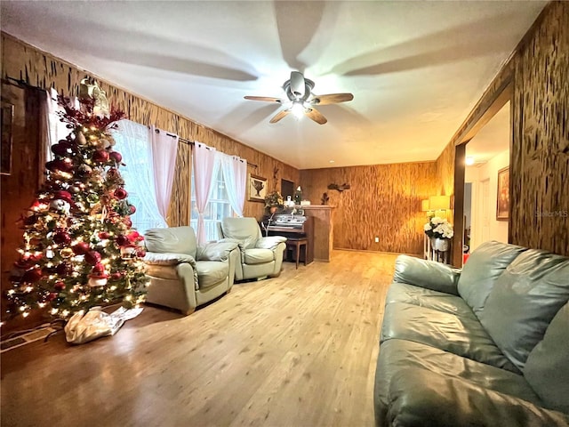 living room featuring light hardwood / wood-style floors, ceiling fan, and wooden walls