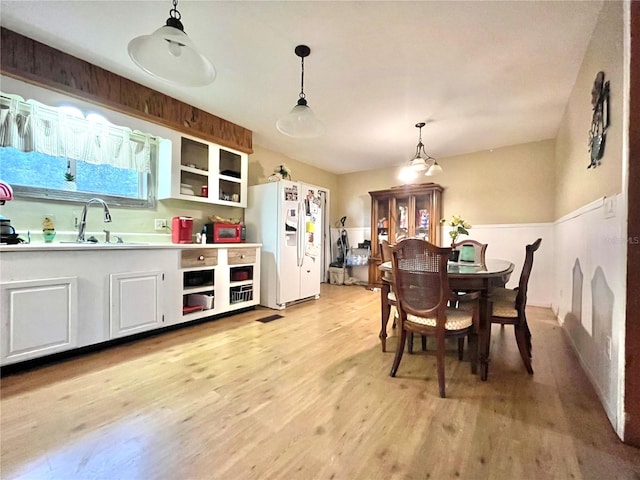 dining area with a chandelier, light hardwood / wood-style floors, and sink