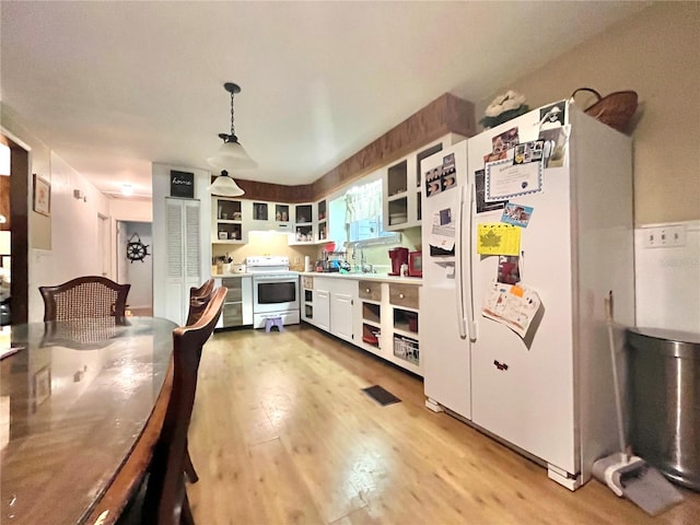 kitchen featuring white cabinetry, sink, pendant lighting, white appliances, and light hardwood / wood-style floors