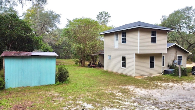 rear view of property featuring a shed and a lawn