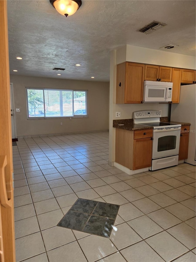 kitchen with a textured ceiling, white appliances, and light tile patterned floors