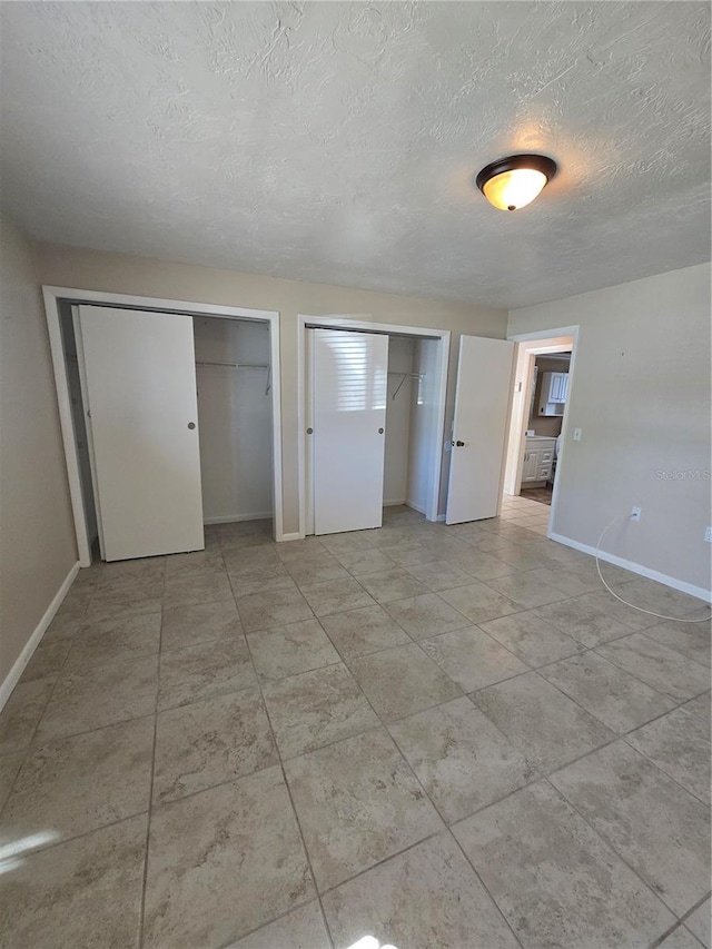 unfurnished bedroom with multiple closets and a textured ceiling