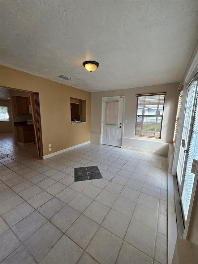 unfurnished room with plenty of natural light, light tile patterned flooring, and a textured ceiling