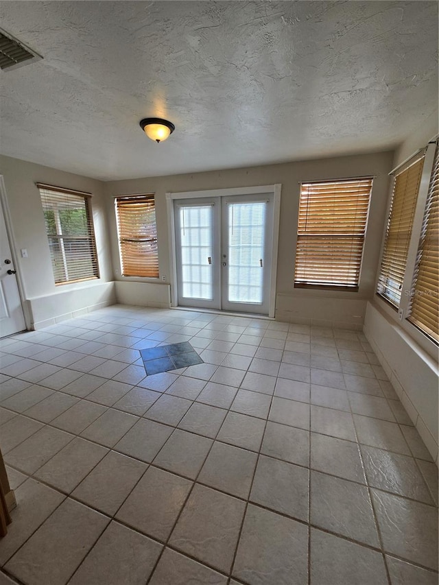 interior space featuring a textured ceiling, french doors, and light tile patterned flooring