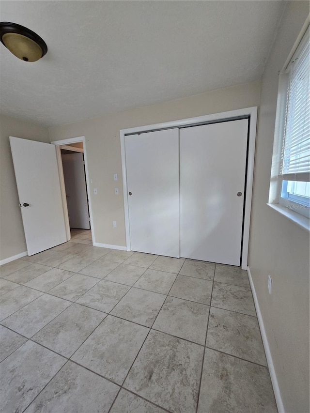 unfurnished bedroom featuring light tile patterned floors and a closet