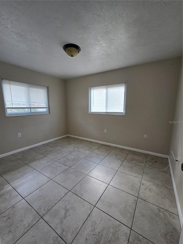 tiled empty room featuring a textured ceiling