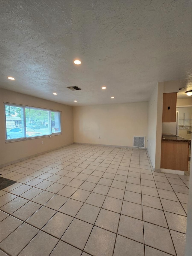 unfurnished room featuring light tile patterned floors and a textured ceiling