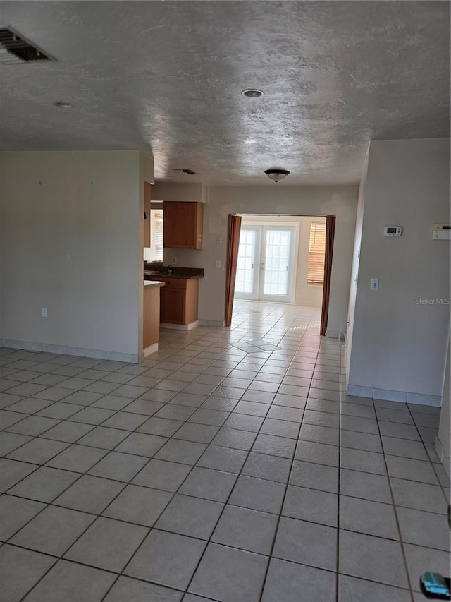 unfurnished living room with light tile patterned flooring and a textured ceiling