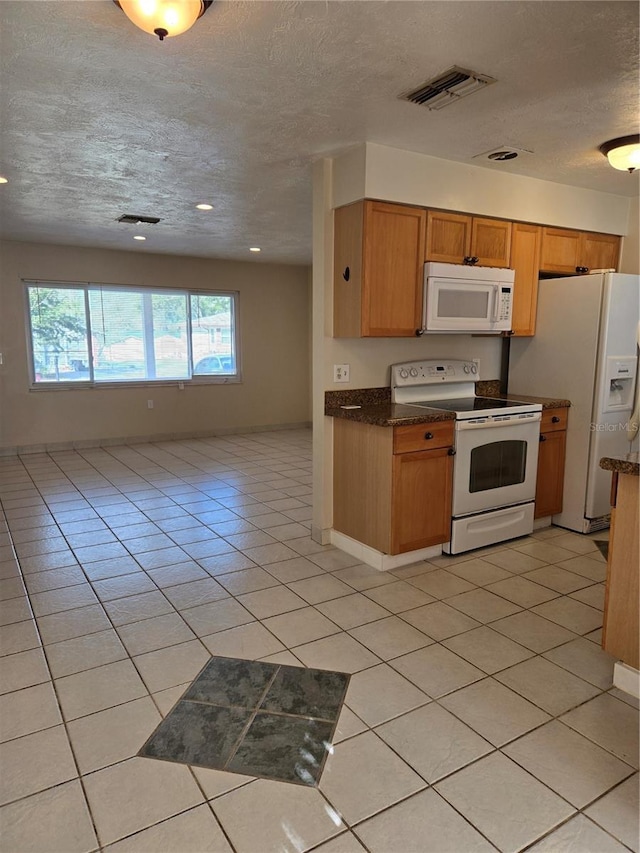 kitchen featuring light tile patterned flooring, white appliances, and a healthy amount of sunlight