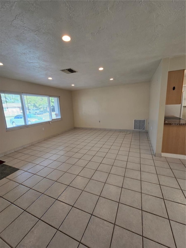 tiled empty room with a textured ceiling