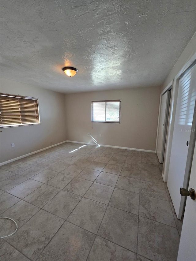 tiled spare room with a textured ceiling