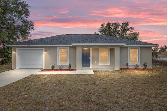 single story home featuring stucco siding, a shingled roof, a lawn, a garage, and driveway