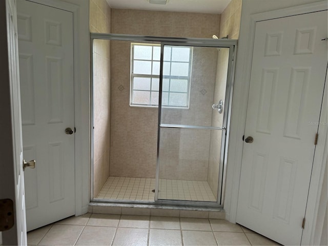 bathroom with a shower with shower door and tile patterned floors