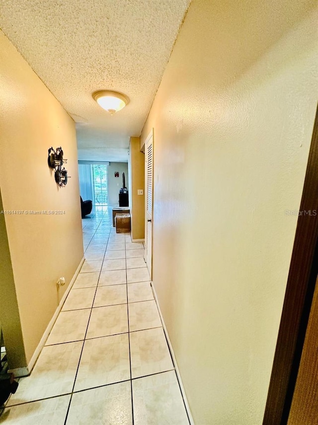 corridor featuring light tile patterned flooring and a textured ceiling