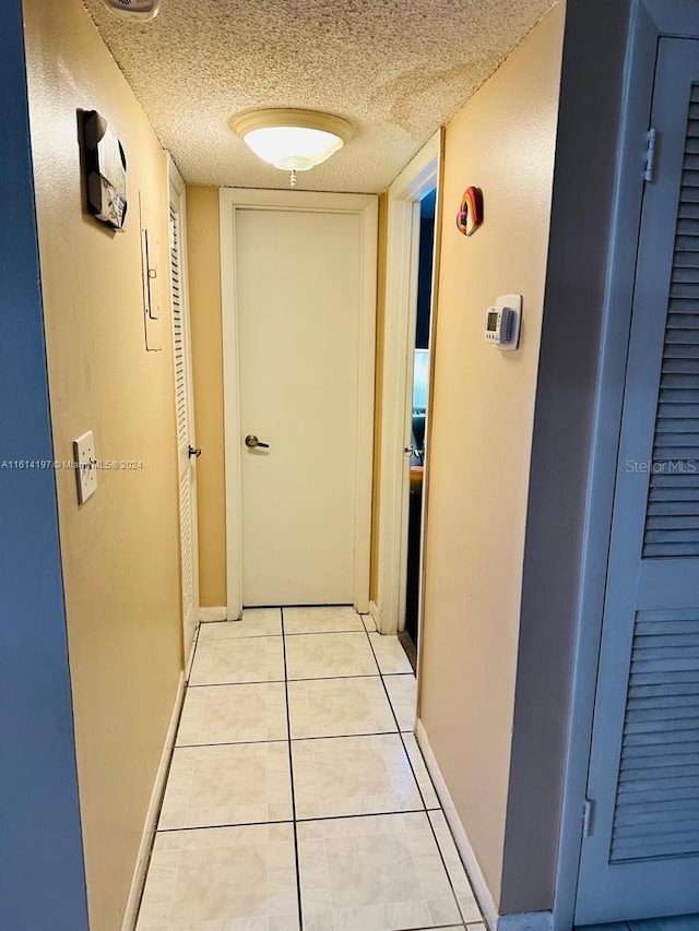 corridor with light tile patterned floors and a textured ceiling