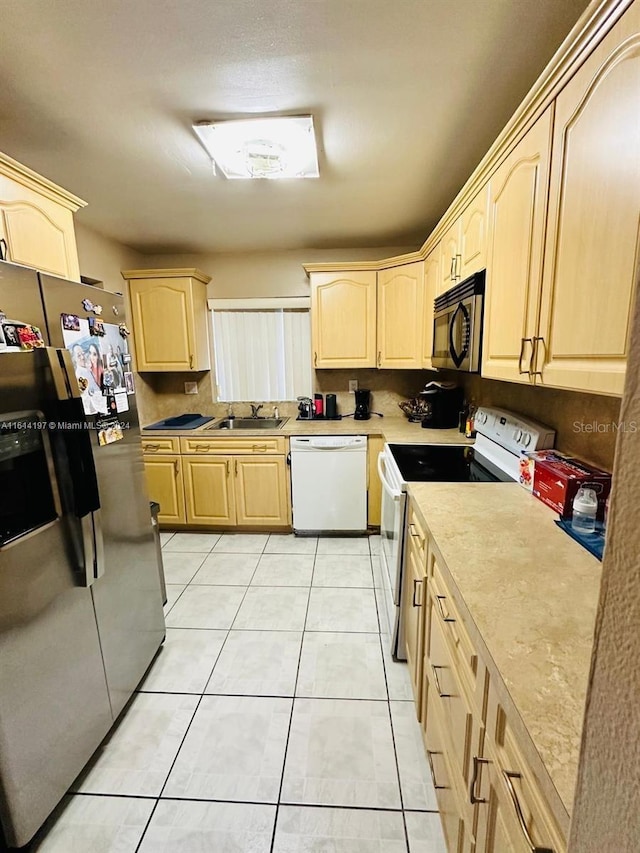 kitchen featuring appliances with stainless steel finishes, light tile patterned floors, light brown cabinetry, and sink