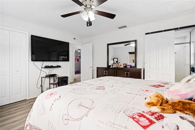 bedroom with ceiling fan, light wood-type flooring, and multiple closets