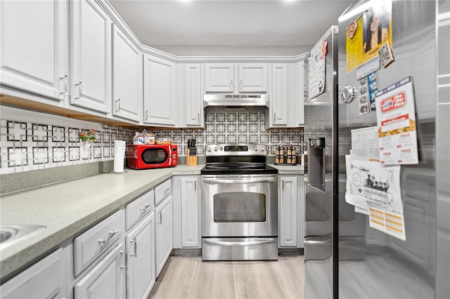 kitchen featuring white cabinets, decorative backsplash, light wood-type flooring, and appliances with stainless steel finishes