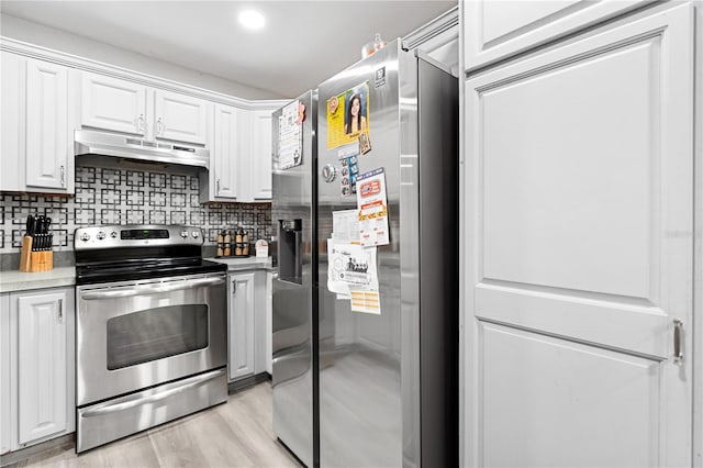 kitchen with tasteful backsplash, light hardwood / wood-style flooring, white cabinets, and appliances with stainless steel finishes