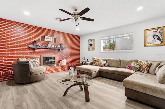 living room featuring a fireplace, hardwood / wood-style flooring, ceiling fan, and brick wall