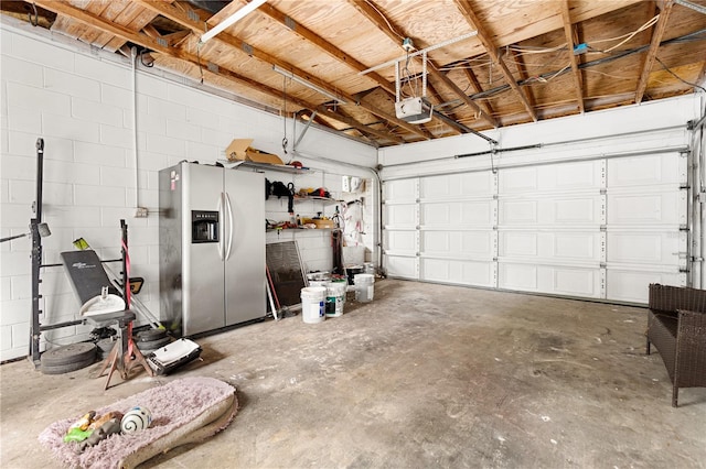 garage with stainless steel refrigerator with ice dispenser and a garage door opener