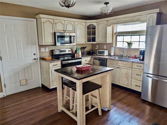 kitchen with a textured ceiling, sink, stainless steel appliances, and dark wood-type flooring