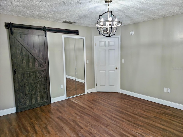 interior space featuring a textured ceiling, a barn door, and dark hardwood / wood-style floors