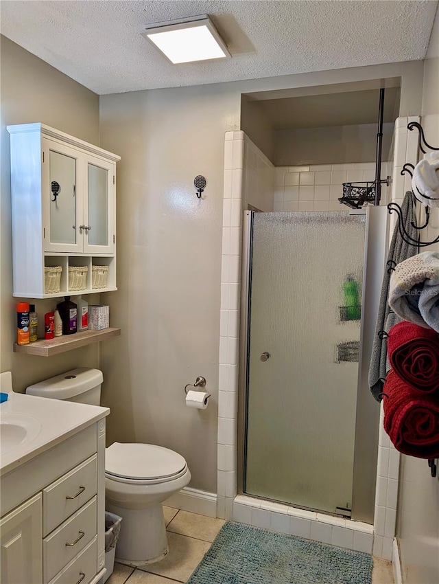 bathroom with tile patterned floors, a textured ceiling, toilet, a shower with door, and vanity