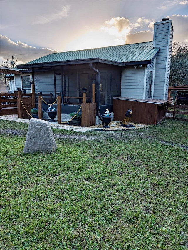 back house at dusk featuring a yard and a sunroom